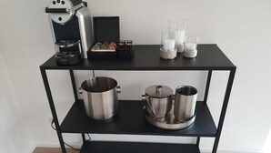 A black metal shelf with a coffee machine, two stainless steel pots, two stainless steel cups, and a small blue booklet. - Le Bijou Bahnhofstrasse / Paradeplatz LB18B (Zürich)