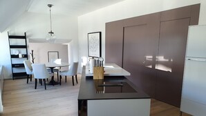 A modern kitchen with a central island, white cabinetry, and a dining area with a round table and chairs. - Le Bijou Bahnhofstrasse / Paradeplatz LB18B (Zürich)