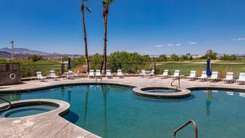 A swimming pool with lounge chairs and palm trees.