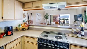 Una cocina moderna con armarios de madera, una estufa de acero inoxidable y un comedor con vistas al exterior.