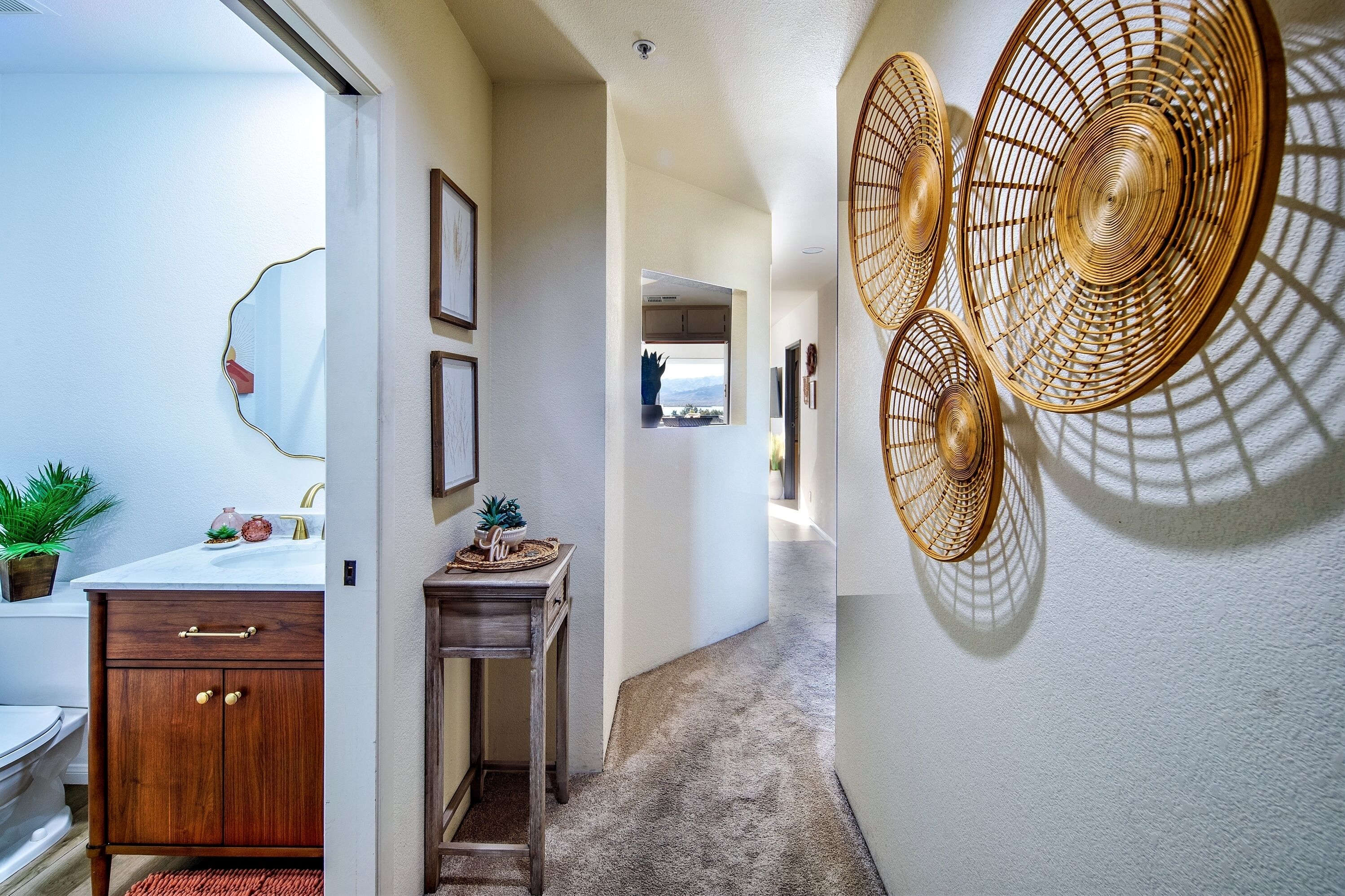Un pasillo con un armario de madera, una mesita y ventiladores fijados a la pared.
