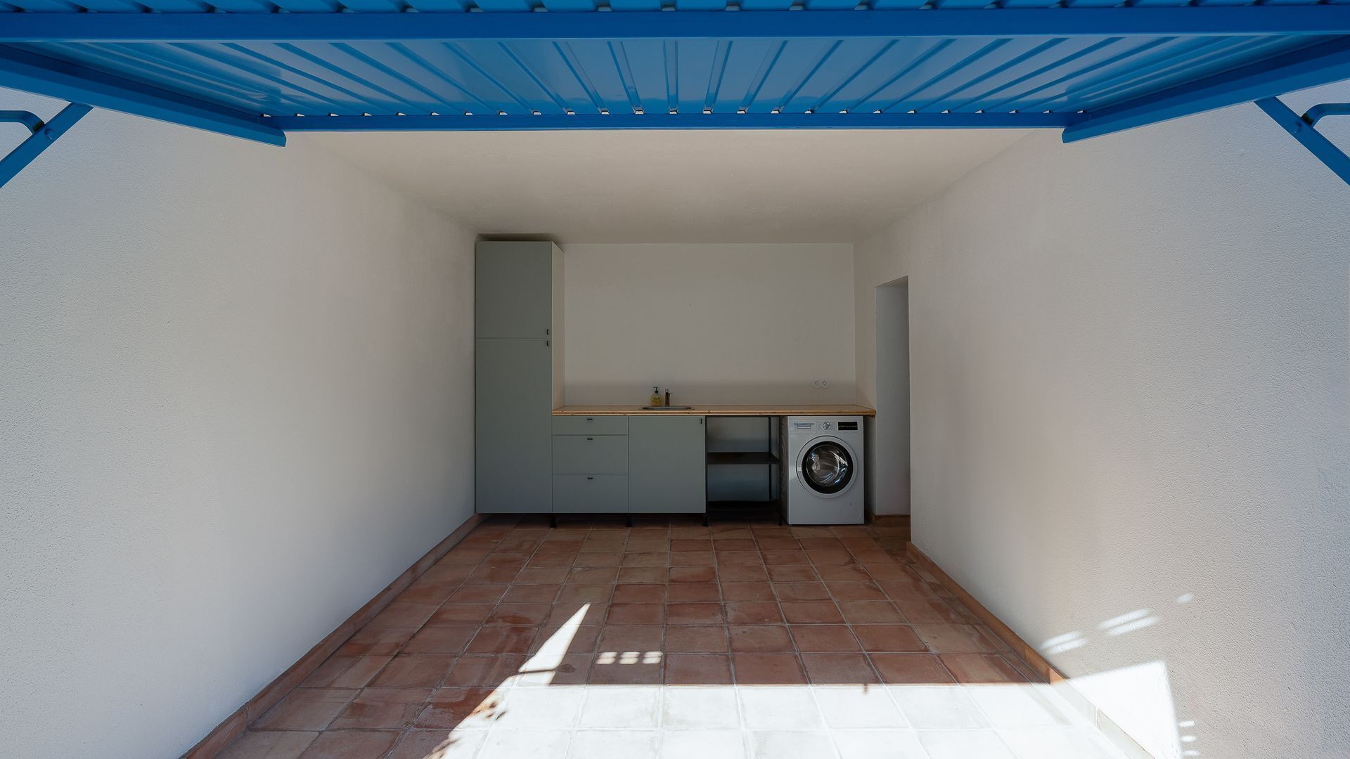 Une cuisine compacte équipée d’un lave-linge, d’un évier et de placards.