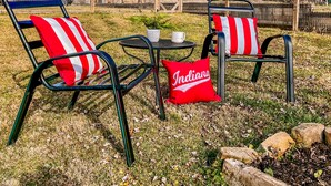 Two outdoor metal chairs with red and white striped cushions, a small table with a white mug, and a red pillow with "Indiana" written on it. - The Blue Door Bungalow - Central & Walkable to Downtown & Indiana University (Bloomington)