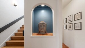 A staircase with a Buddha statue in a niche, framed artwork on the wall, and a handrail. - Overlook Oasis-Stunning Views-Pool and Spa! (Austin)
