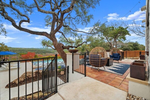 A patio with outdoor seating, a pool, and a view of the landscape.