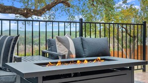 A patio with a fire feature, outdoor seating, and a view of the landscape. - Overlook Oasis-Stunning Views-Pool and Spa! (Austin)