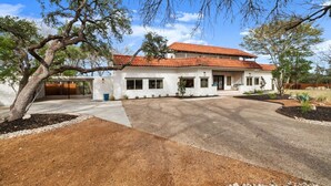 A single-story house with a red-tiled roof, a covered patio, and a driveway leading to the entrance. - Overlook Oasis-Stunning Views-Pool and Spa! (Austin)