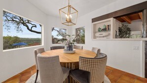 A dining area with a round table, chairs, and a hanging light fixture. - Overlook Oasis-Stunning Views-Pool and Spa! (Austin)