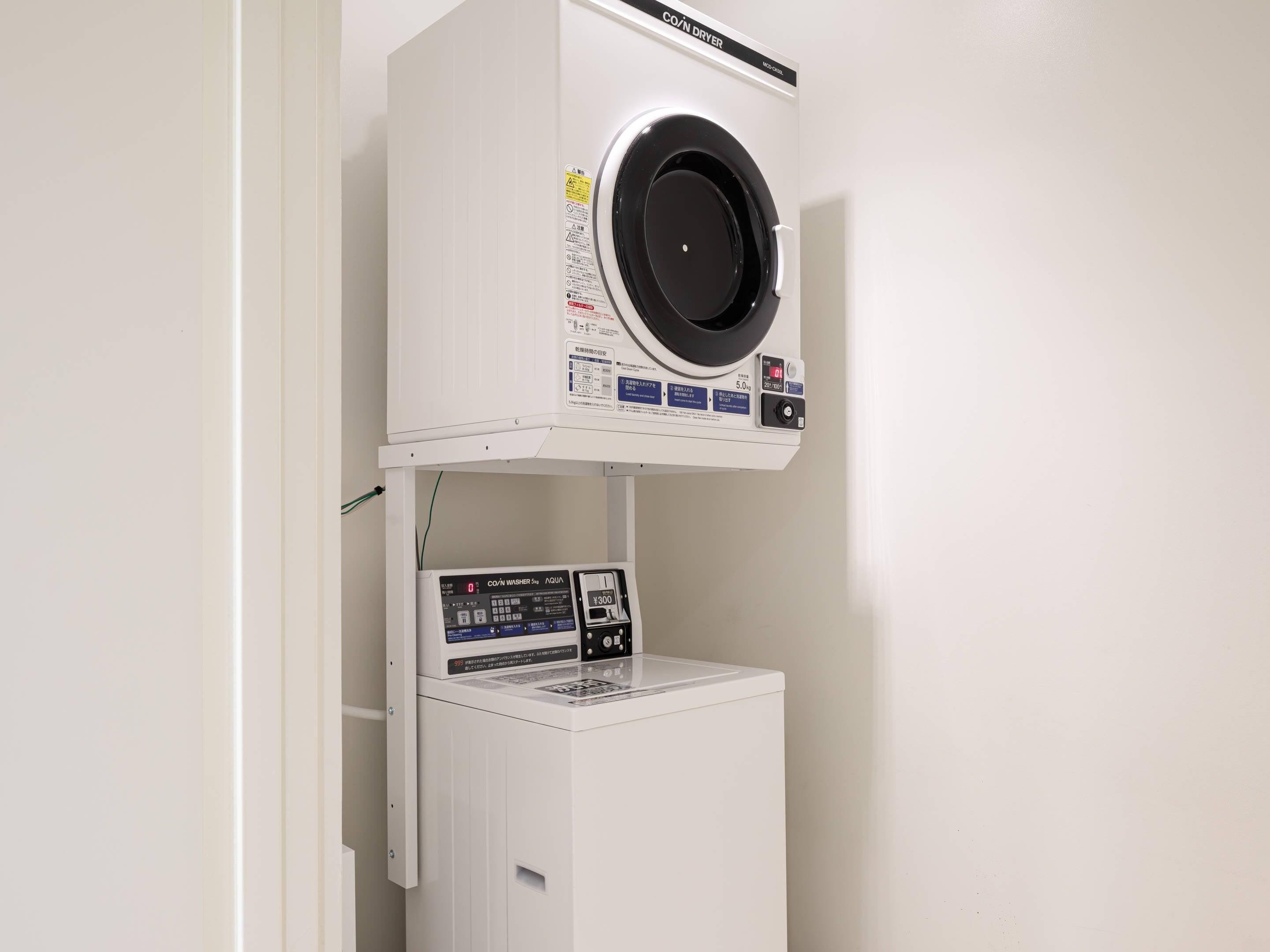 Lavadora y secadora compacta de color blanco, montada en la pared, con panel de control digital y un pequeño compartimento de almacenamiento debajo.