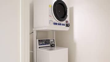 Lavadora y secadora compacta de color blanco, montada en la pared, con panel de control digital y un pequeño compartimento de almacenamiento debajo.