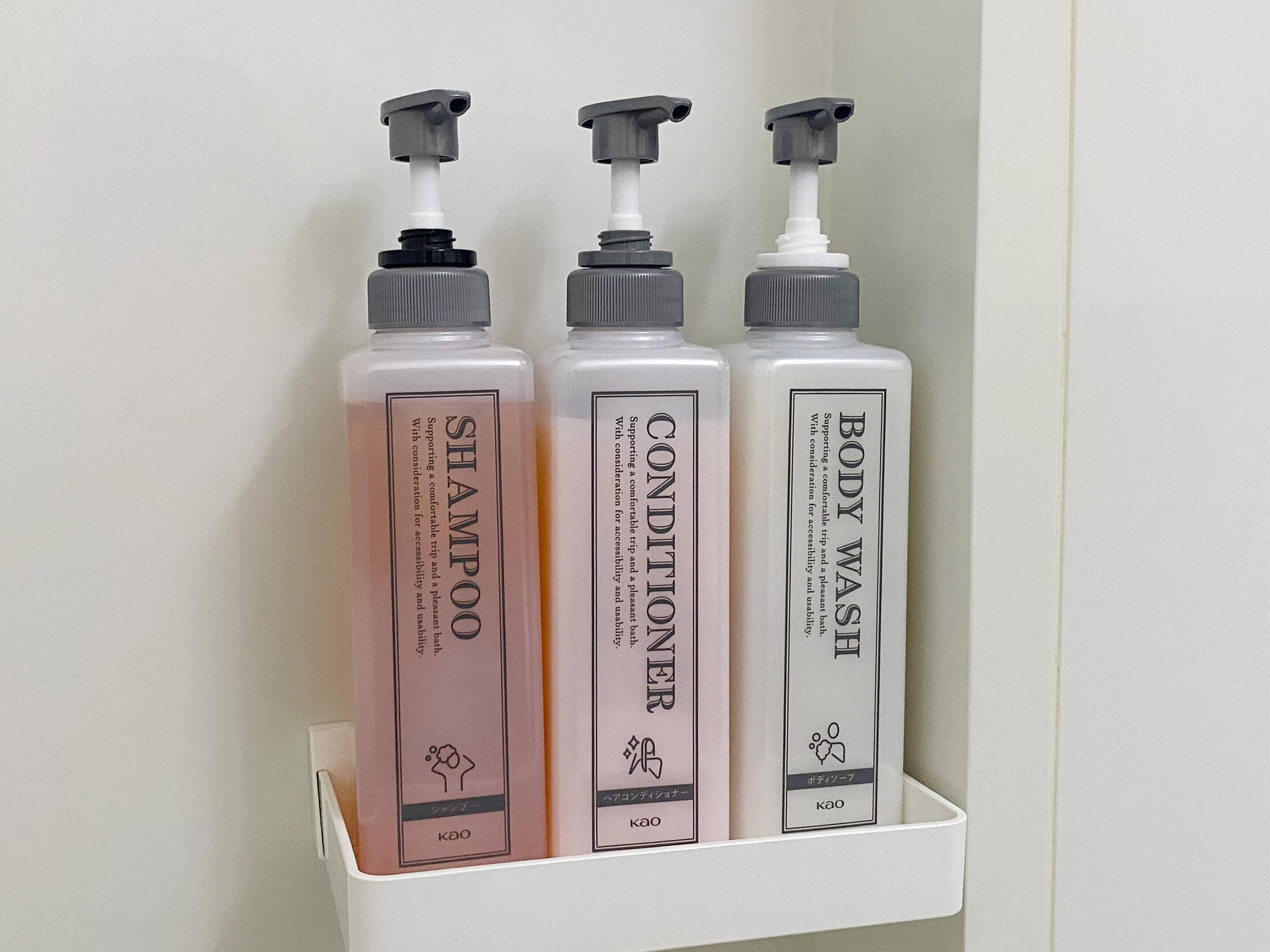 Three toiletry bottles on a white shelf.