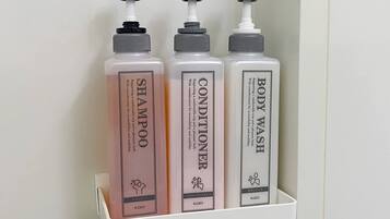 Three toiletry bottles on a white shelf.