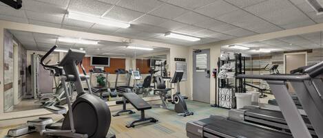 A gym with treadmills, elliptical machines, and a mirrored wall.