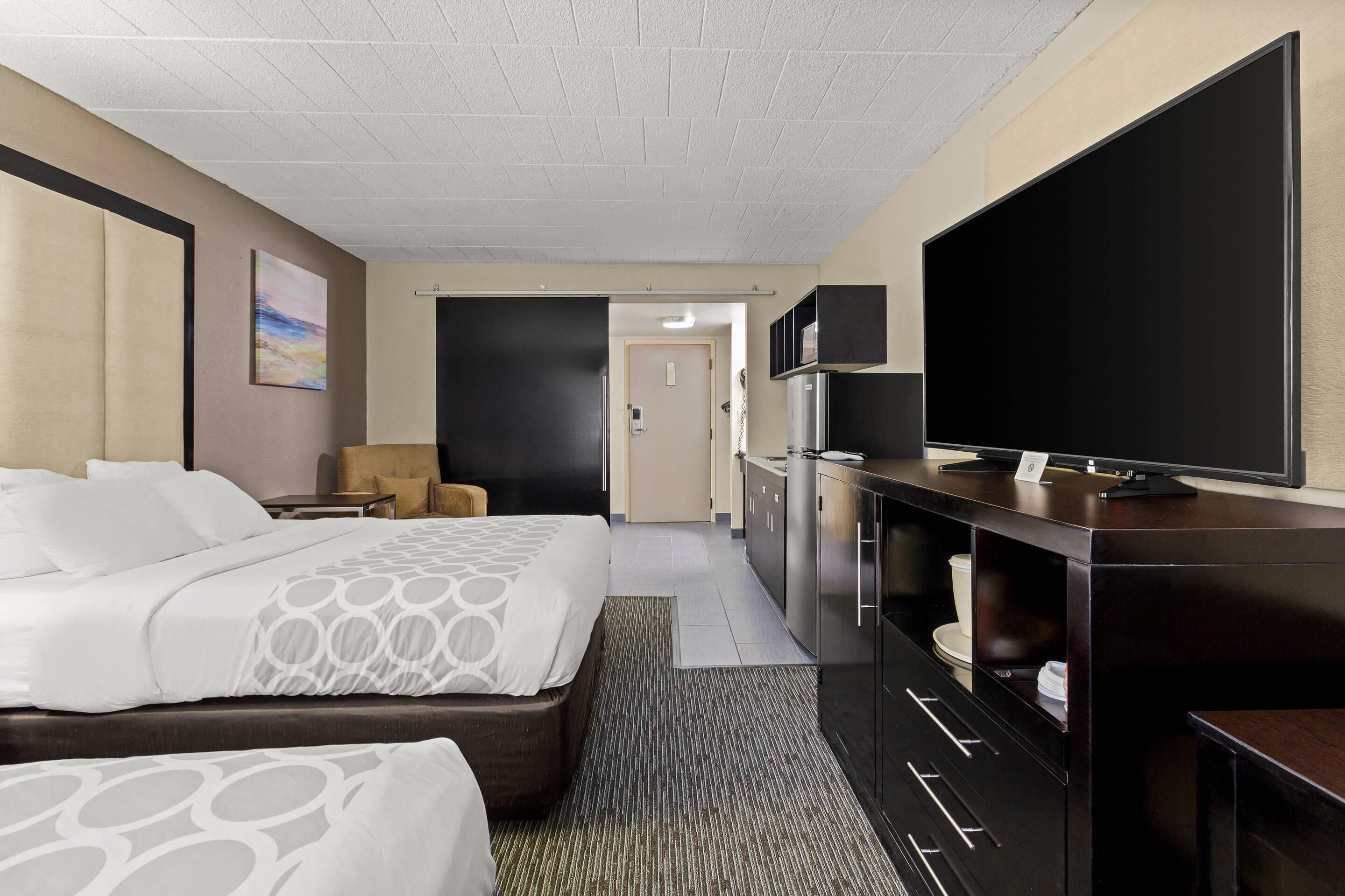 Una habitación de hotel con una cama grande, televisión, escritorio y minibar.