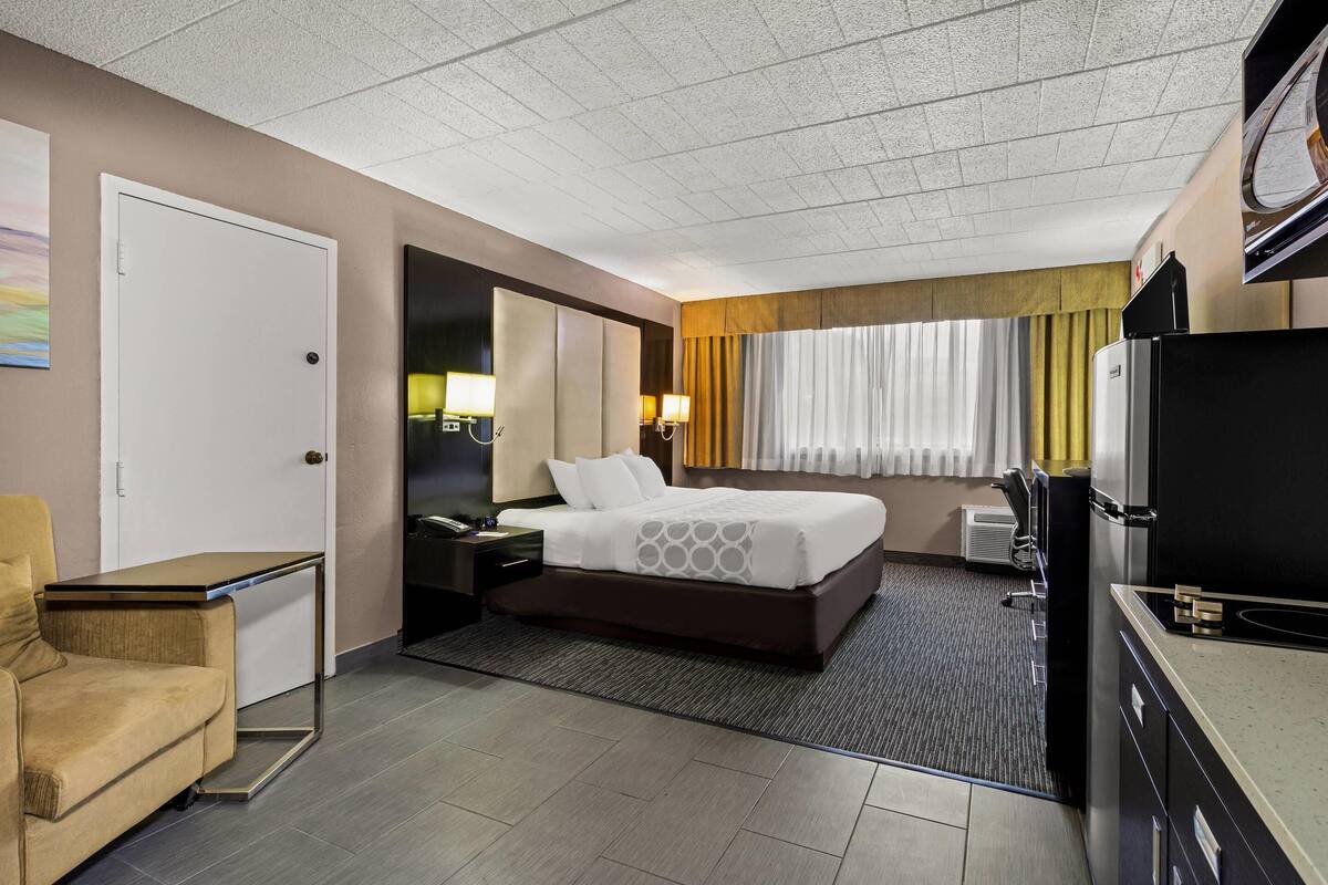 A hotel room with a bed, a desk, a chair, a television, and a window with curtains.