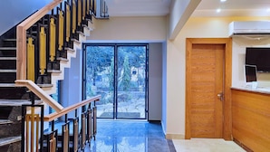 Een modern interieur met een houten trap, een grote glazen deur naar buiten en een houten deur met een ingebouwde televisie.