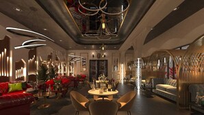 Een moderne hotellobby met een ronde centrale tafel, rode banken en eigentijdse verlichting.