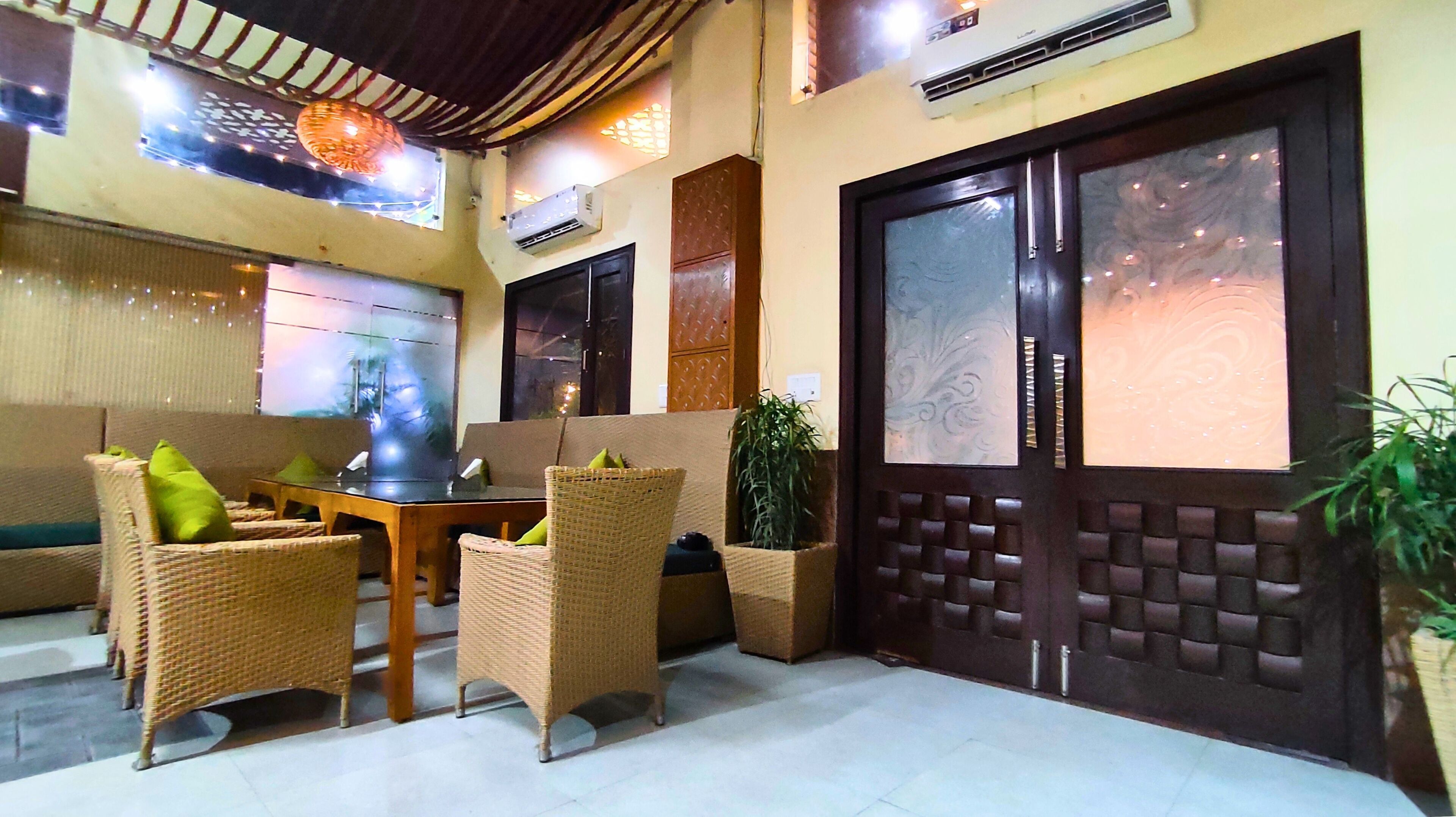 Un vestíbulo con muebles de mimbre, una mesa de vidrio y una puerta decorativa grande.