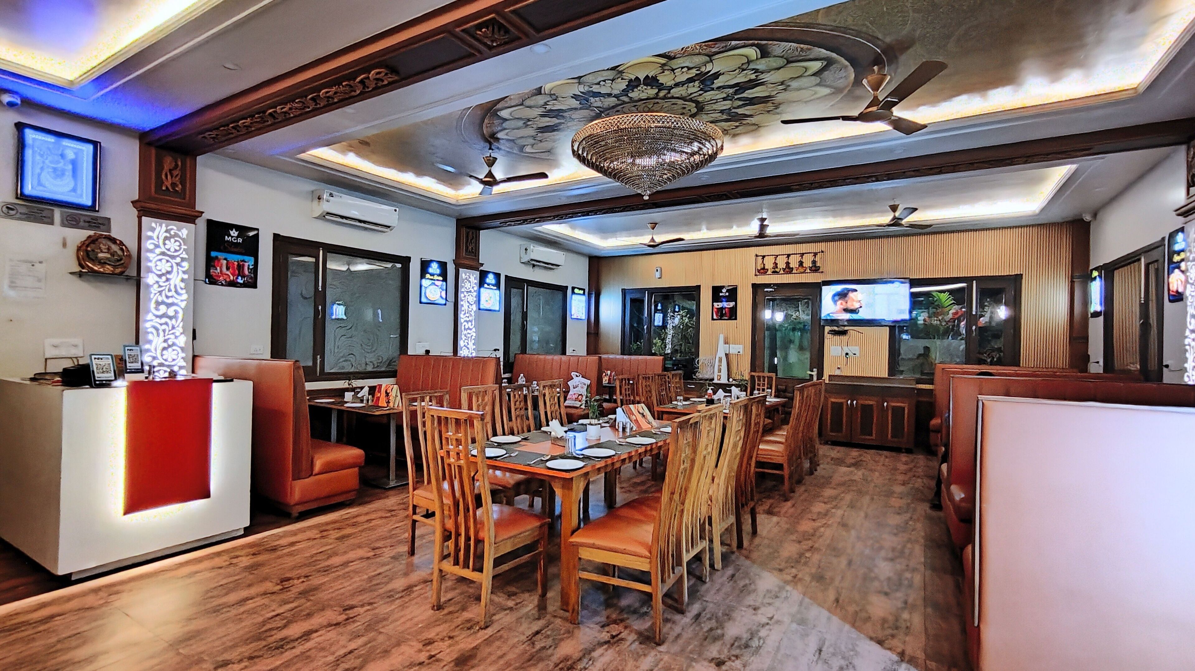 A restaurant with wooden furniture, a reception desk, and a ceiling with a decorative design.
