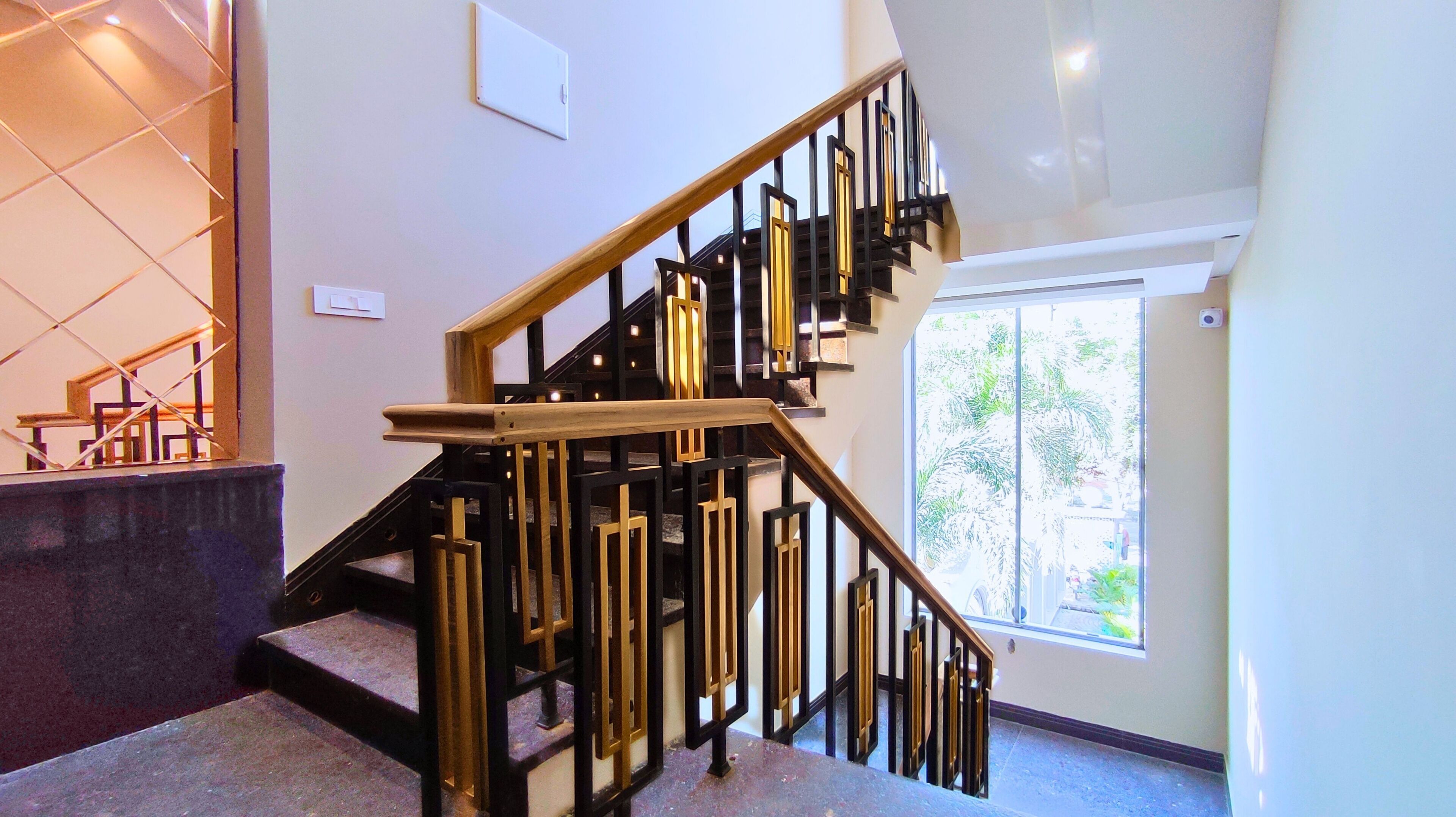 A modern staircase with a wooden handrail and black metal railings.