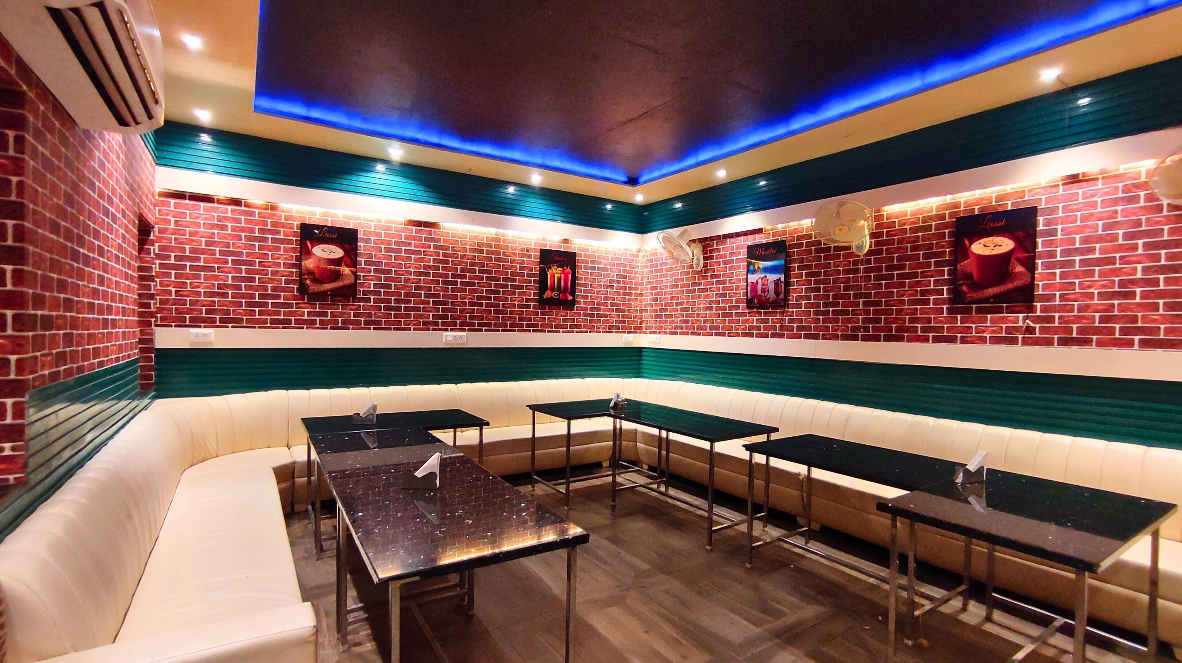 A restaurant with brick walls, green and white seating, and multiple tables.