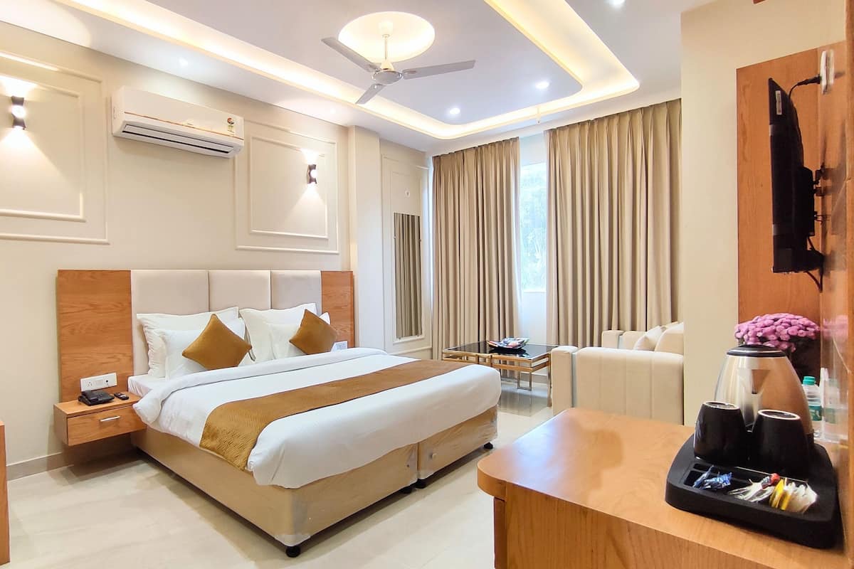 Une chambre d’hôtel avec un grand lit, des tables de chevet, un bureau, une chaise, une machine à café et un ventilateur de plafond.