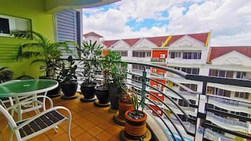 A balcony with potted plants, a table, and chairs.