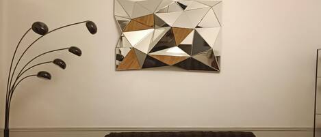 En moderne stue med en mørkebrun sofa, et geometrisk kunstværk og en højtstående gulvlampe.