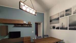 A modern dining area with a wooden table and chairs, a TV on a built-in shelf, and a wall decorated with landscape paintings. - The Arena - Apartment in the Center. Ideal for sightseeing. Metro 100m away (Napoli)