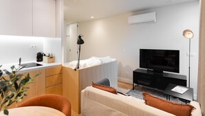 A modern, compact living space with a kitchenette, a sofa, a TV, and a bedside table. - Feel Porto Corporate Housing Boavista V (Porto)