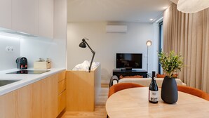 Une cuisine moderne dotée d’un four encastré, un coin repas avec une table et des chaises, un téléviseur et une plante en pot.