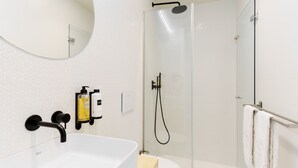 Une salle de bain moderne avec un lavabo blanc, une douche à parois de verre et un miroir au-dessus du lavabo.