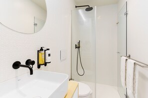 A modern bathroom with a white sink, a glass-enclosed shower, and a mirror above the sink. - Feel Porto Corporate Housing Boavista VI (Porto)