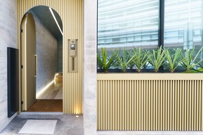 A modern interior with a hallway leading to a door, a wall-mounted plant display, and a large window with blinds. - Feel Porto Corporate Housing Boavista VI (Porto)