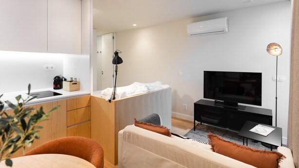 Un salon moderne comprenant un canapé, un téléviseur, un coin repas avec une table et une kitchenette.
