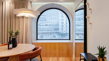 A modern room with a large arched window, a round wooden table, and a potted plant.