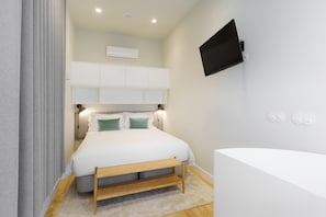 A modern bedroom with a bed, bedside tables, a mounted TV, and a built-in air conditioning unit. - Feel Porto Corporate Housing Boavista III (Porto)