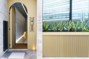 A modern interior with a reception desk, a glass door entrance, and a window with plants. - Feel Porto Corporate Housing Boavista III (Porto)