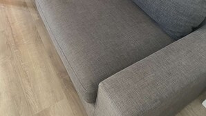 Ein graues Sofa, Holzboden und eine orangefarbene Wand.