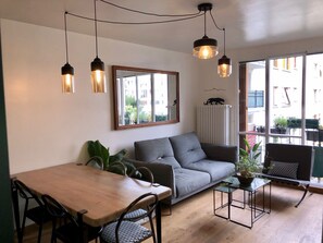 Relax in this stylish living space with a sofa, armchair, and dining table for four, plus a large mirror and glass pendant light.