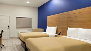 A hotel room with two beds, a wooden headboard, a desk, and a chair. - Scottish Inn Parker (Houston)
