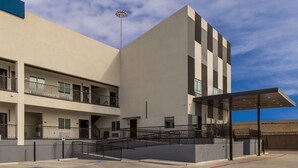 A modern building with a flat facade, multiple balconies, and a covered entrance area. - Scottish Inn Parker (Houston)