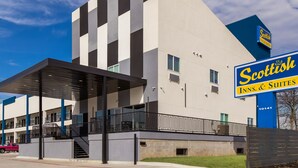 A modern hotel with a prominent sign for 'Scottish Inns & Suites'. - Scottish Inn Parker (Houston)