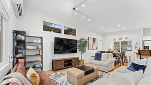 A modern living room with a brown sofa, a white sofa, a coffee table, and a TV mounted on the wall. - Pool/Hot Tub/75 inch TV/1000mbps/Brand New (Grants Pass)