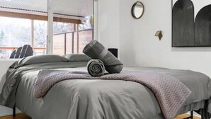 A modern bedroom with a large bed, a window, and a minimalist decor. - Pool/Hot Tub/75 inch TV/1000mbps/Brand New (Grants Pass)