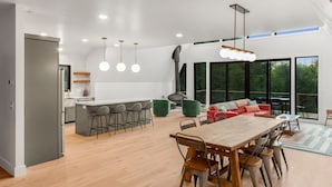 Une cuisine spacieuse dotée d’un îlot central, de tabourets de bar et de luminaires suspendus.