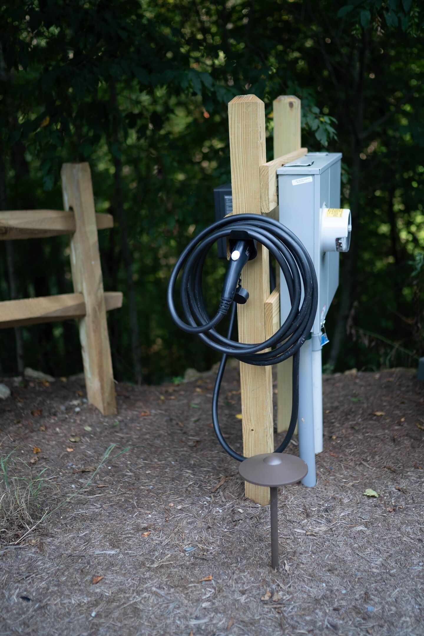 A utility box mounted on a wooden post with a coiled cable attached.