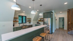 A modern kitchen with a large island, bar stools, and stainless steel appliances. - Cozy A-Frame Cabin - In-Deck Hot Tub - near Boone (Vilas)