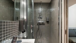 A modern bathroom with a glass-enclosed shower, a white sink, and a tiled floor.