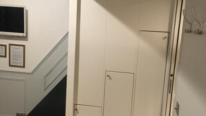 A hallway with a wooden floor, white walls, and a door with a handle.